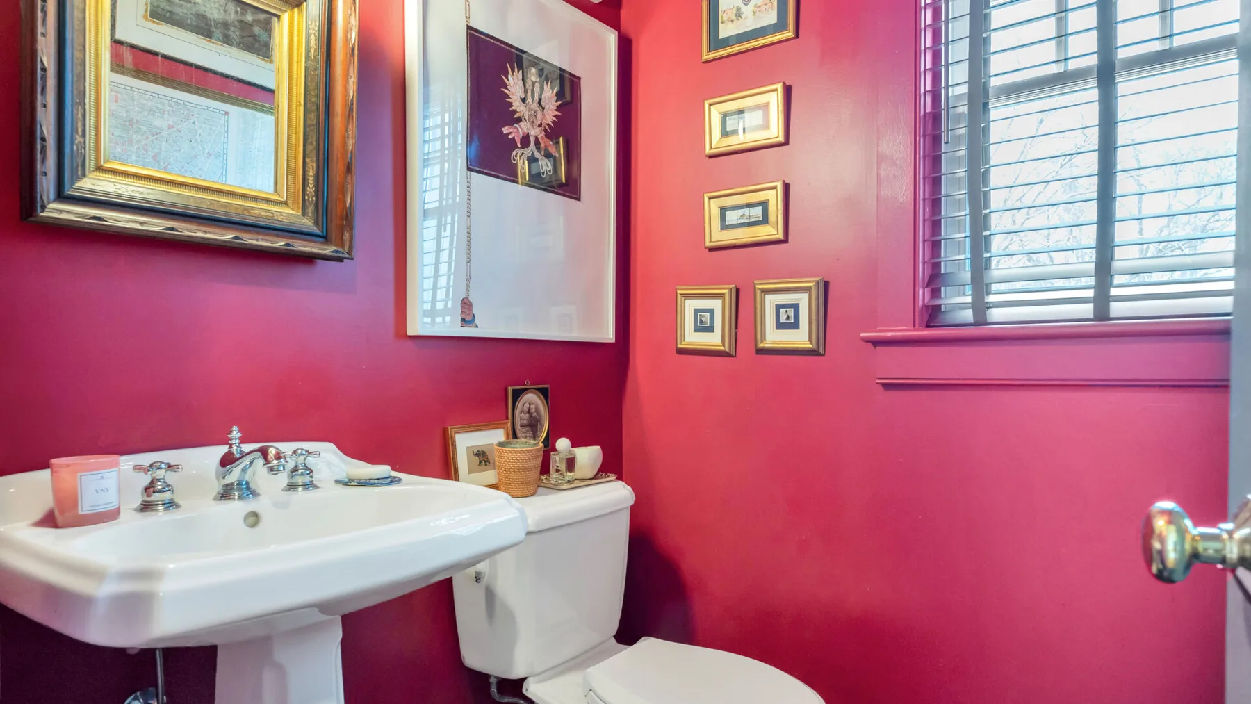 Un baño con lavabo blanco, inodoro y paredes de color rosa intenso.