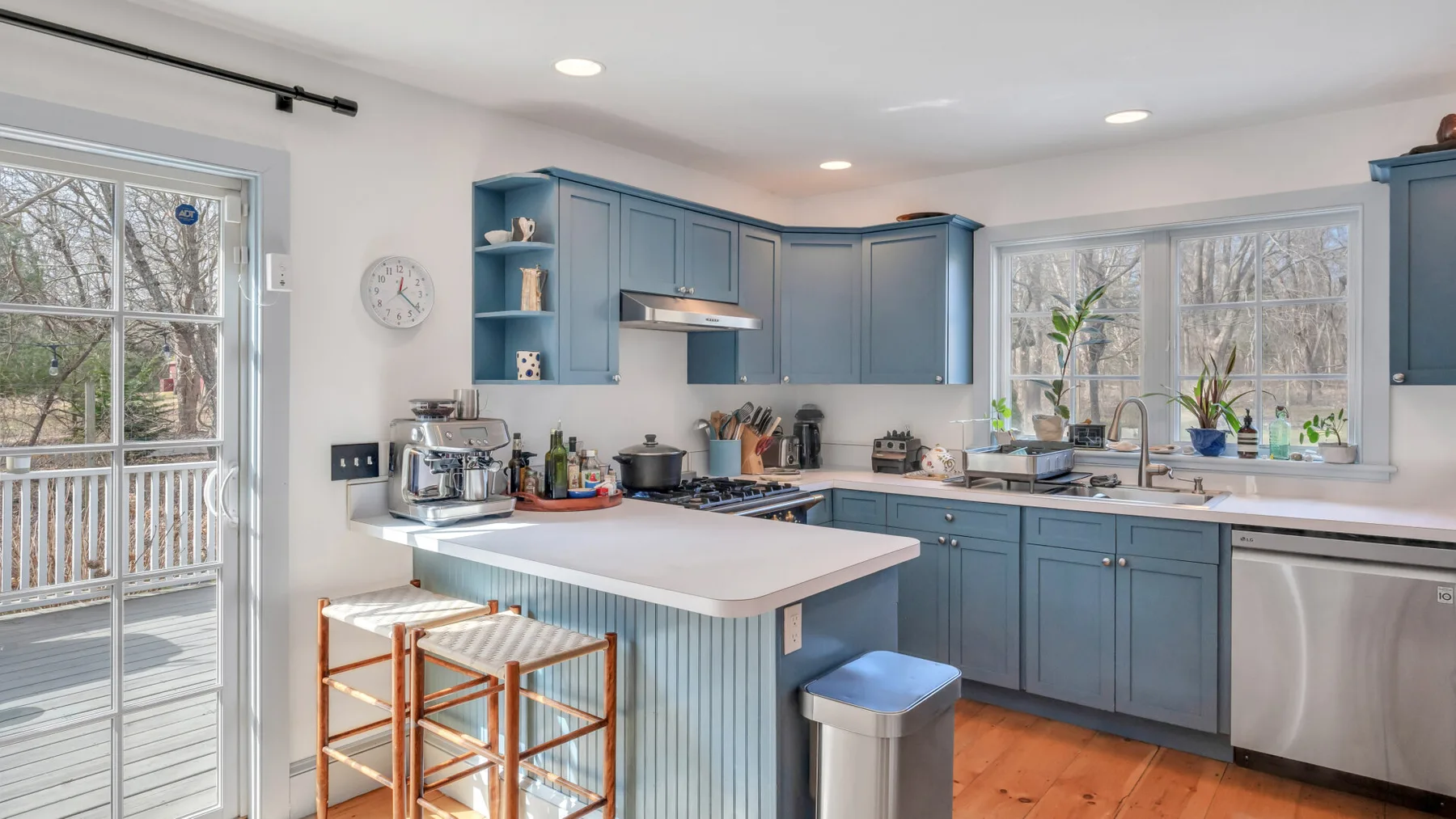Una cocina luminosa con gabinetes azules, una isla central y grandes ventanas.