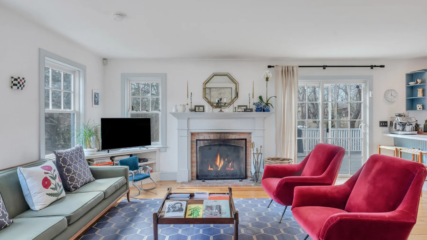 Una sala luminosa con chimenea, asientos y puertas de vidrio que dan a un patio.