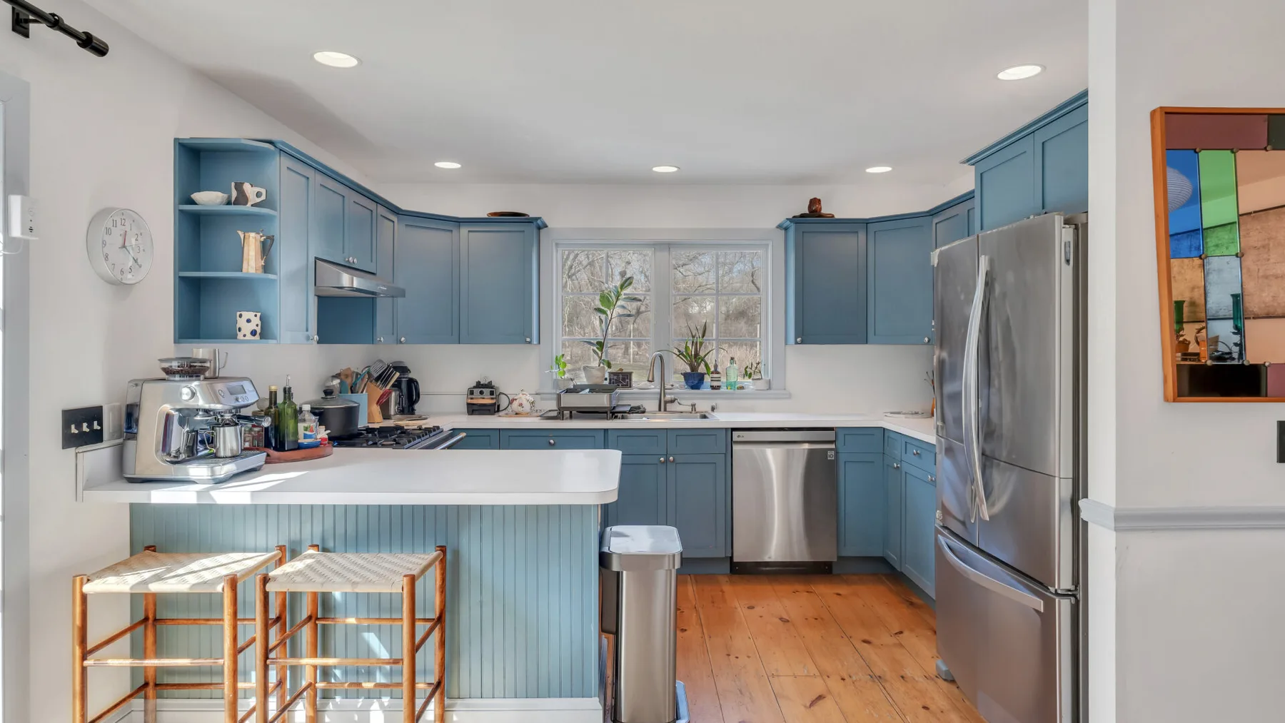 Una cocina luminosa con gabinetes azules, una isla central y electrodomésticos de acero inoxidable.