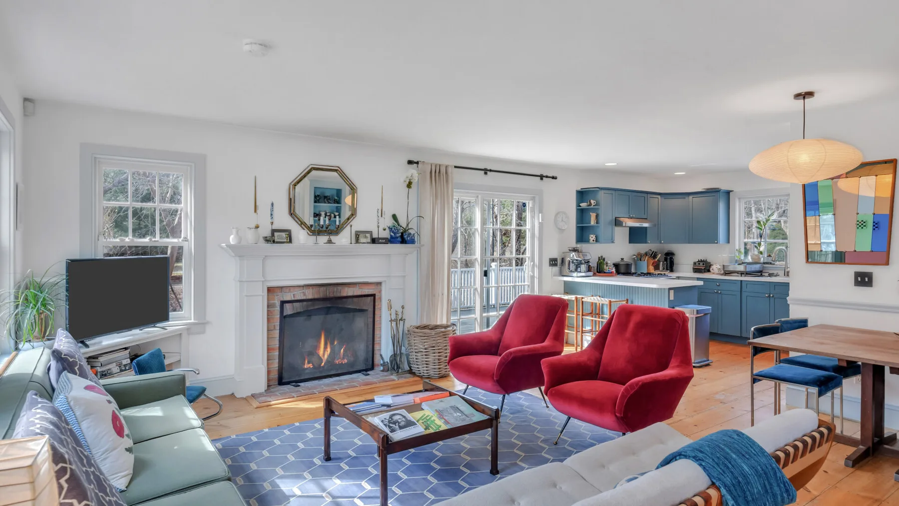 Una sala de estar con asientos rojos y chimenea se abre a una cocina azul.