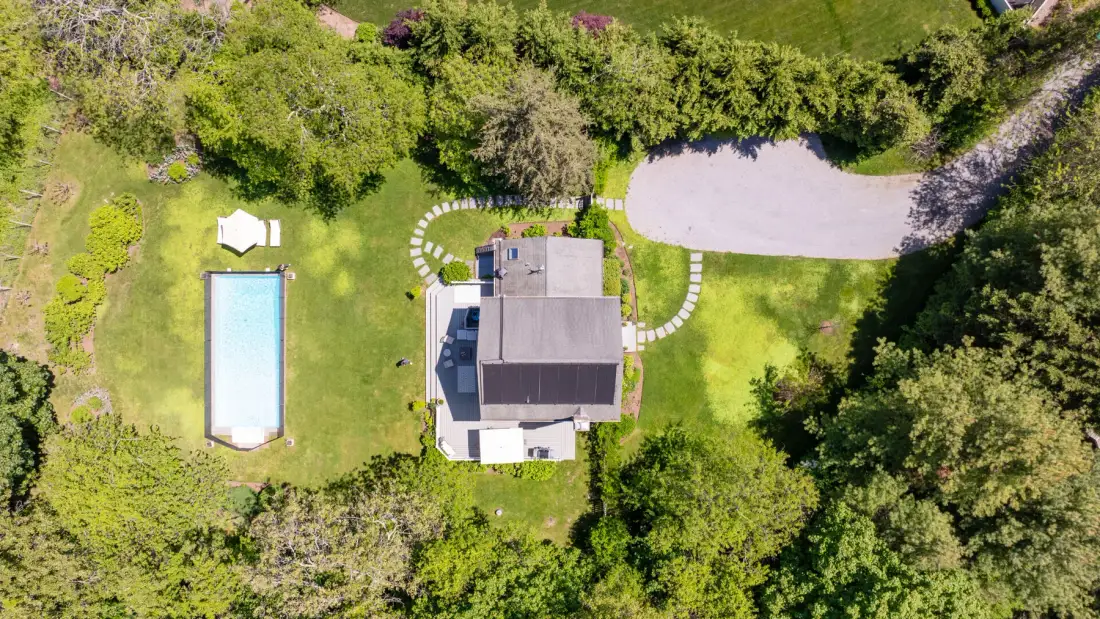 Vista aérea de una casa, una piscina y jardines.