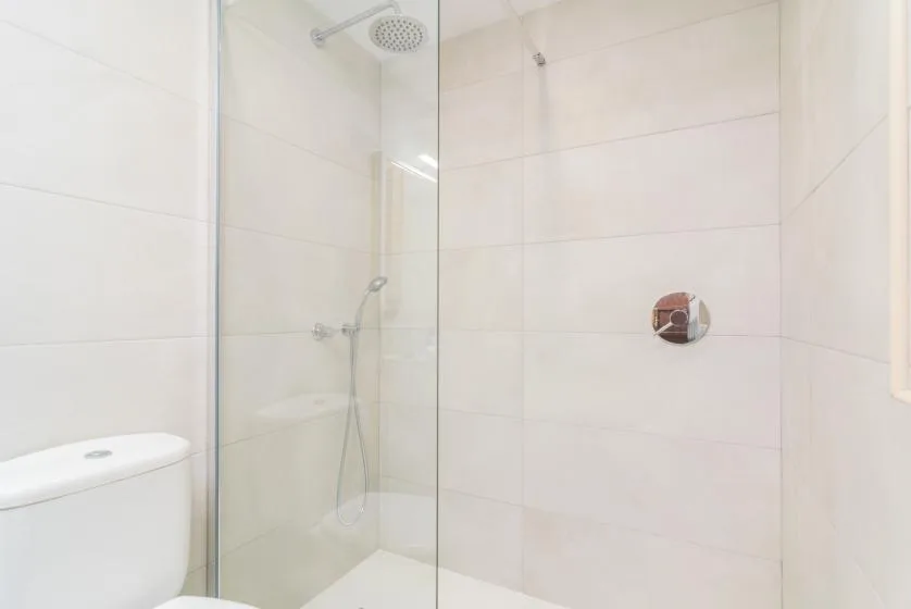A bright tiled bathroom with a glass shower and toilet.