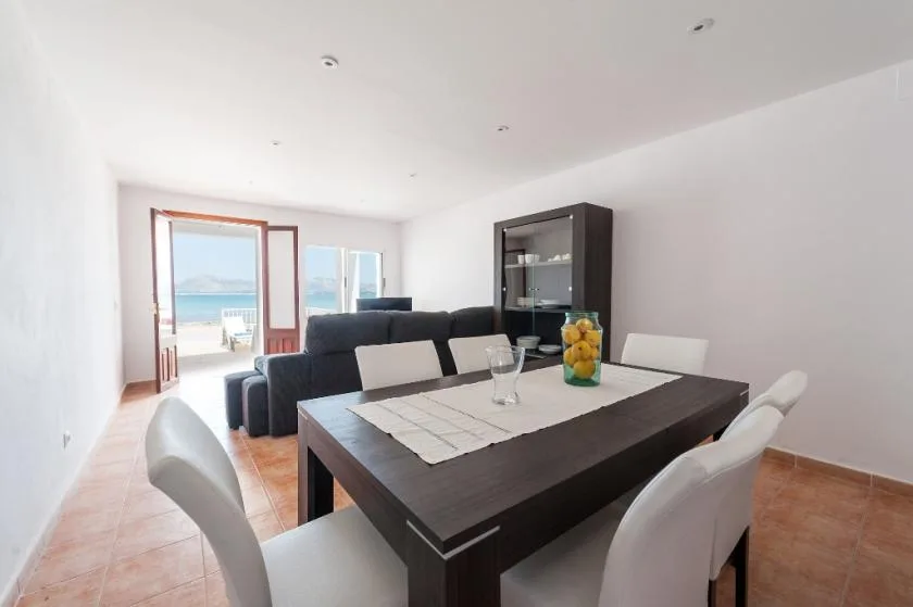 A dining area with a dark table and seating beside a bright living area.