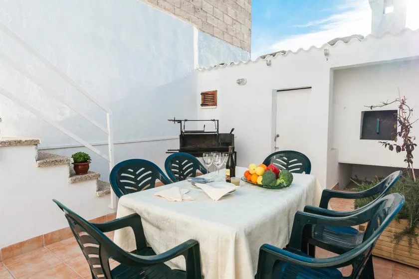 A rooftop dining area has a table set with dishes and surrounded by chairs.
