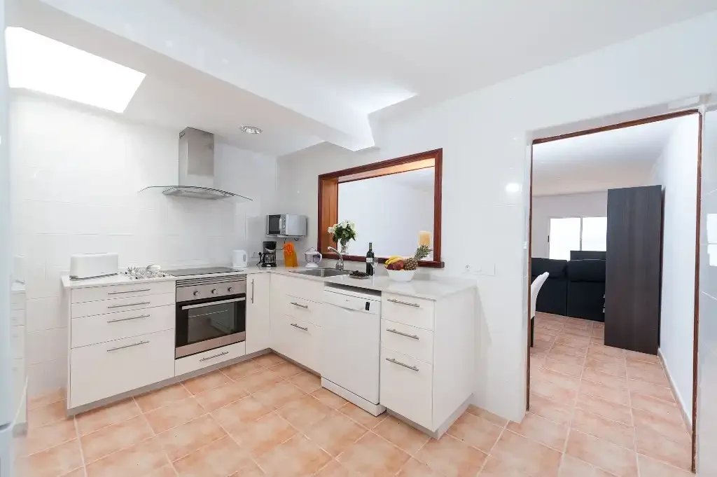 A bright kitchen with white cabinets and a countertop.