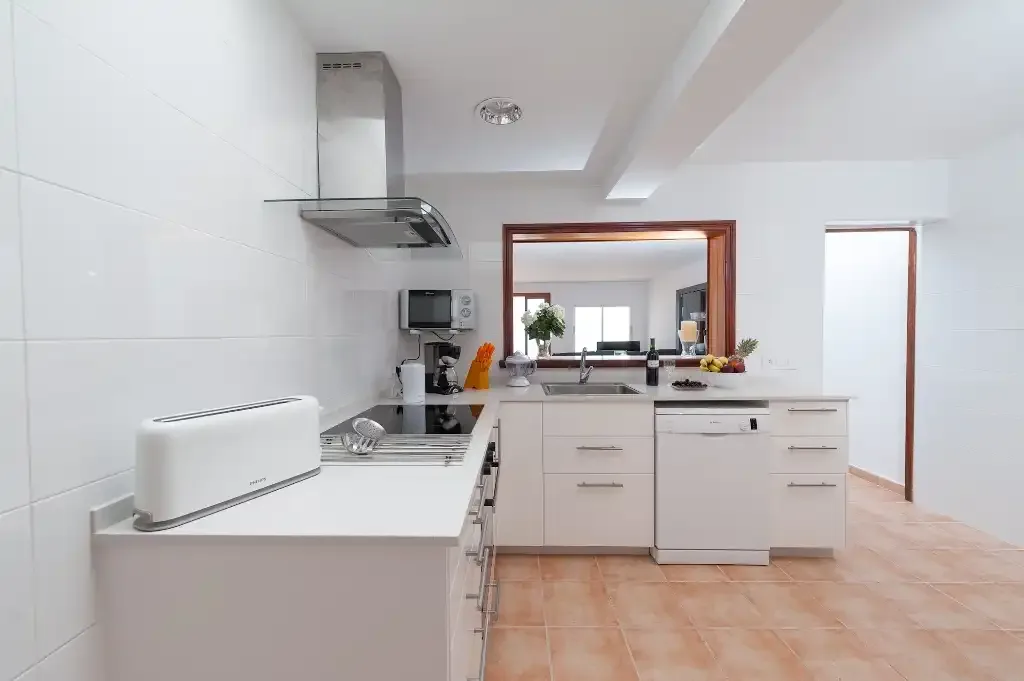 A bright kitchen with white cabinetry, a countertop, and a range hood.
