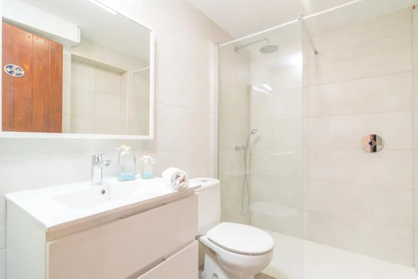 A bright bathroom with a vanity, toilet, and glass shower.