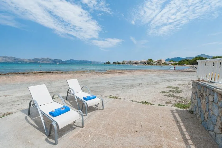 A seaside terrace with two lounge chairs facing the water.