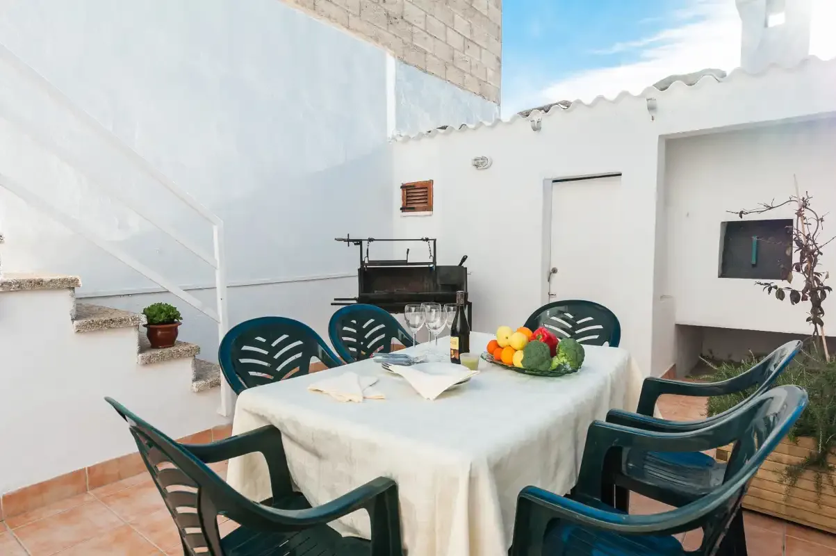 A courtyard dining area with a set table and dark outdoor seating.