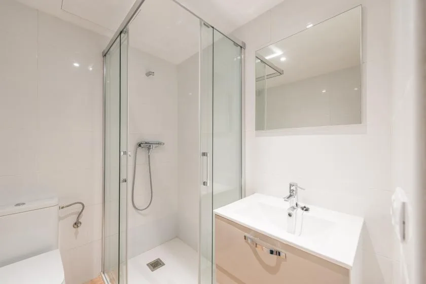 A bright bathroom with a glass shower and a white sink vanity.