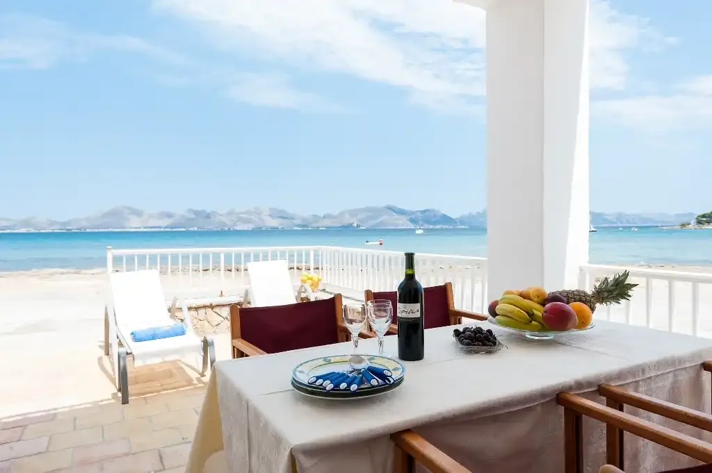 A seaside dining table overlooks a sandy beach and calm blue water.