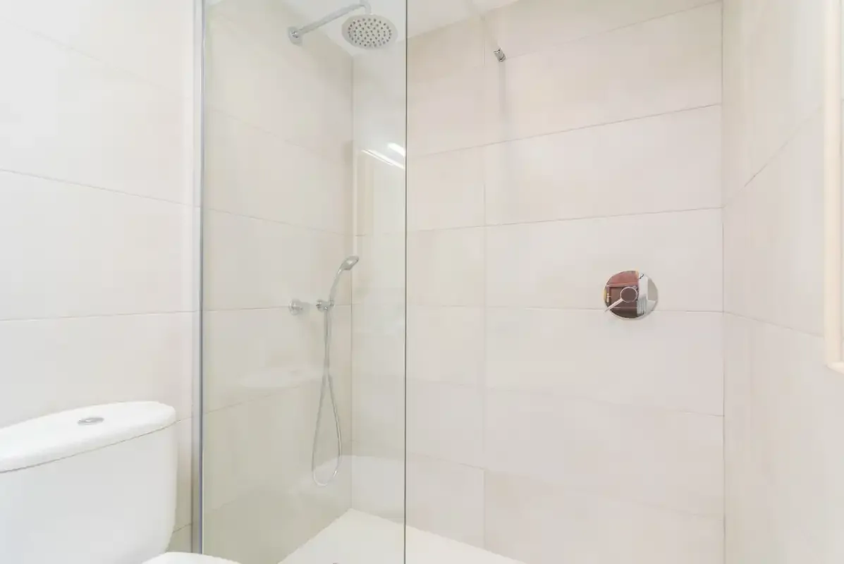 A tiled bathroom with a glass shower and toilet.