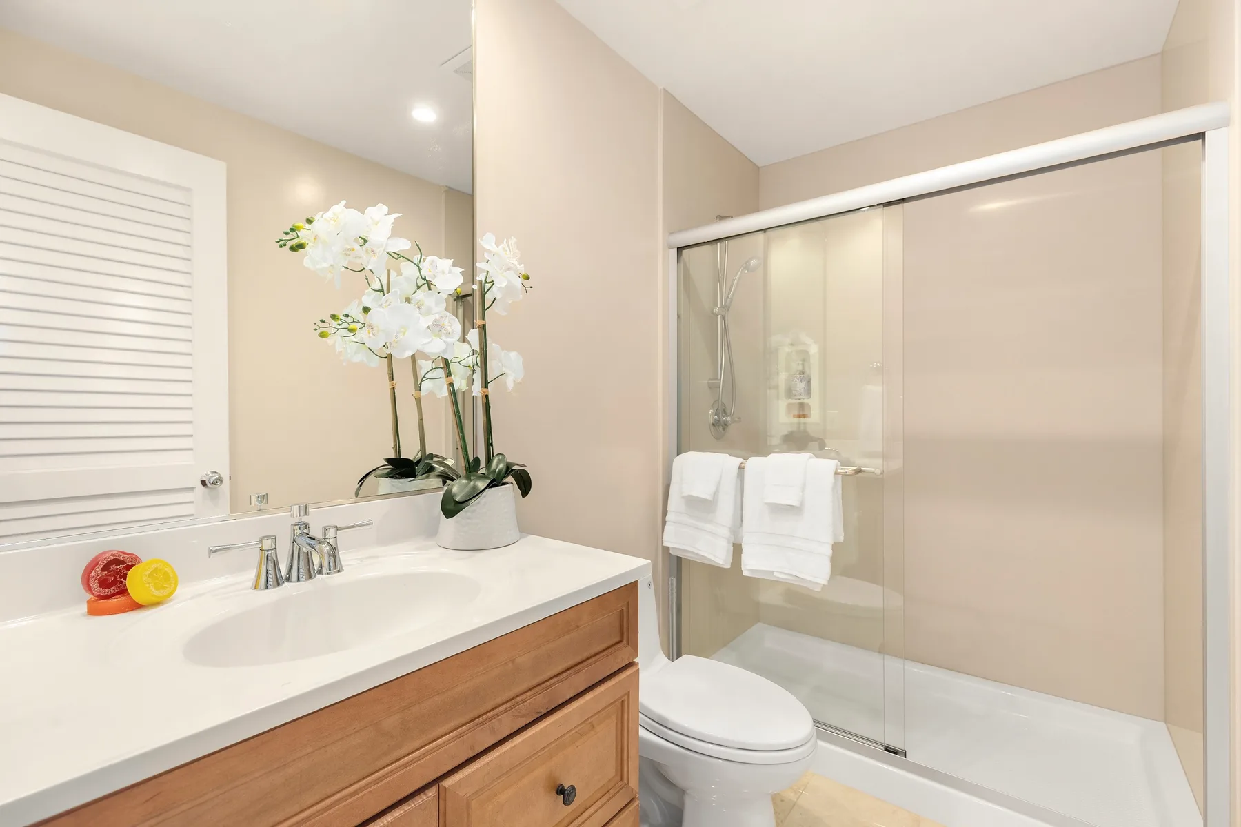 Un baño con lavabo, mueble de tocador y ducha con mampara de vidrio.