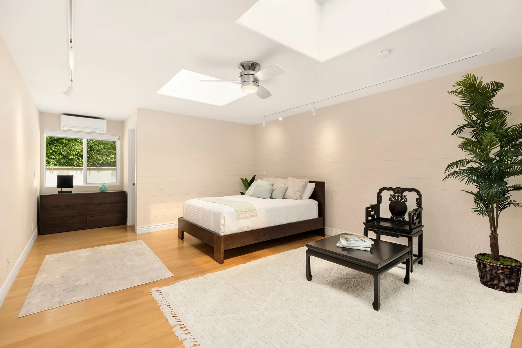 Un dormitorio luminoso con una cama, una mesa pequeña y una planta en maceta.