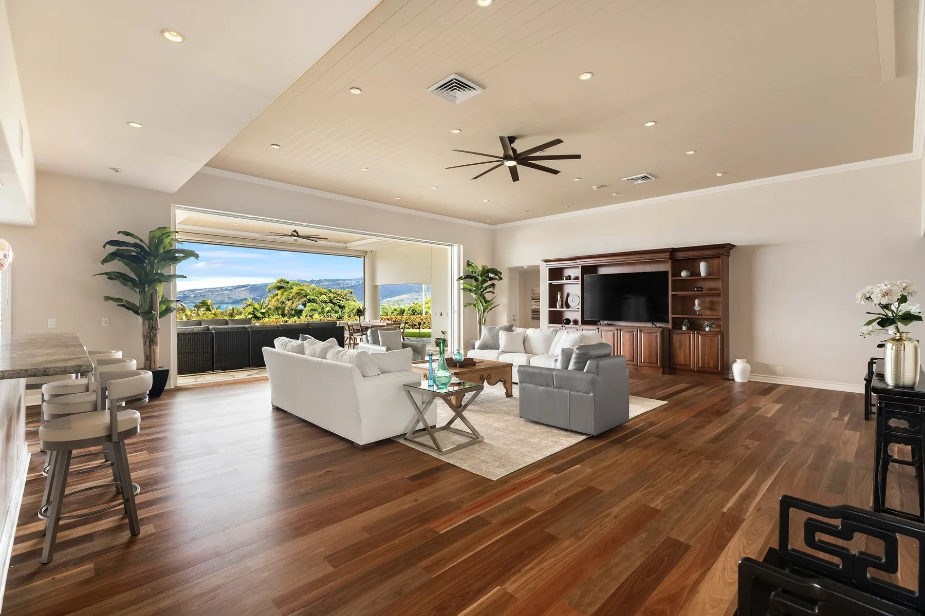 Una sala de estar amplia con asientos y una gran ventana con vista a la vegetación.