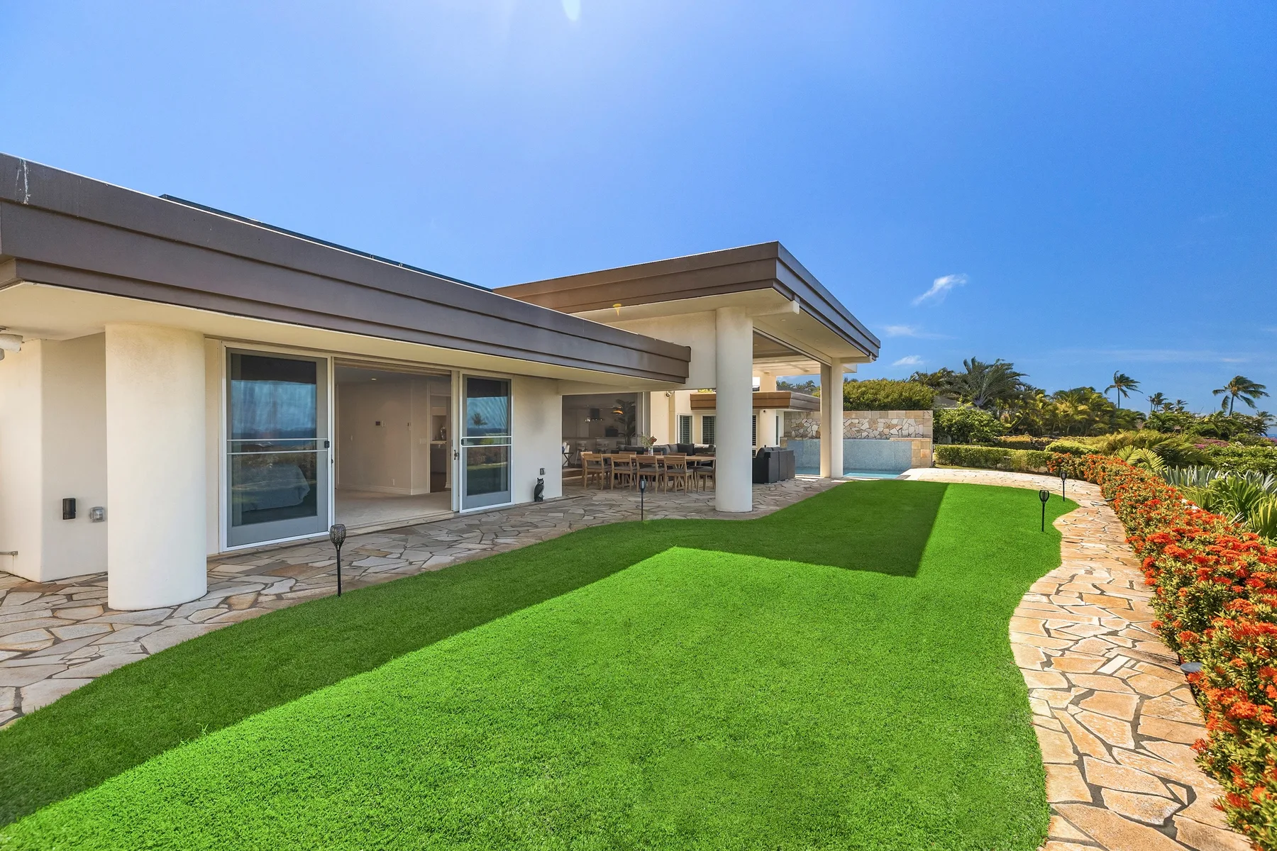 Una casa moderna se abre a un césped verde y un sendero curvo de piedra.