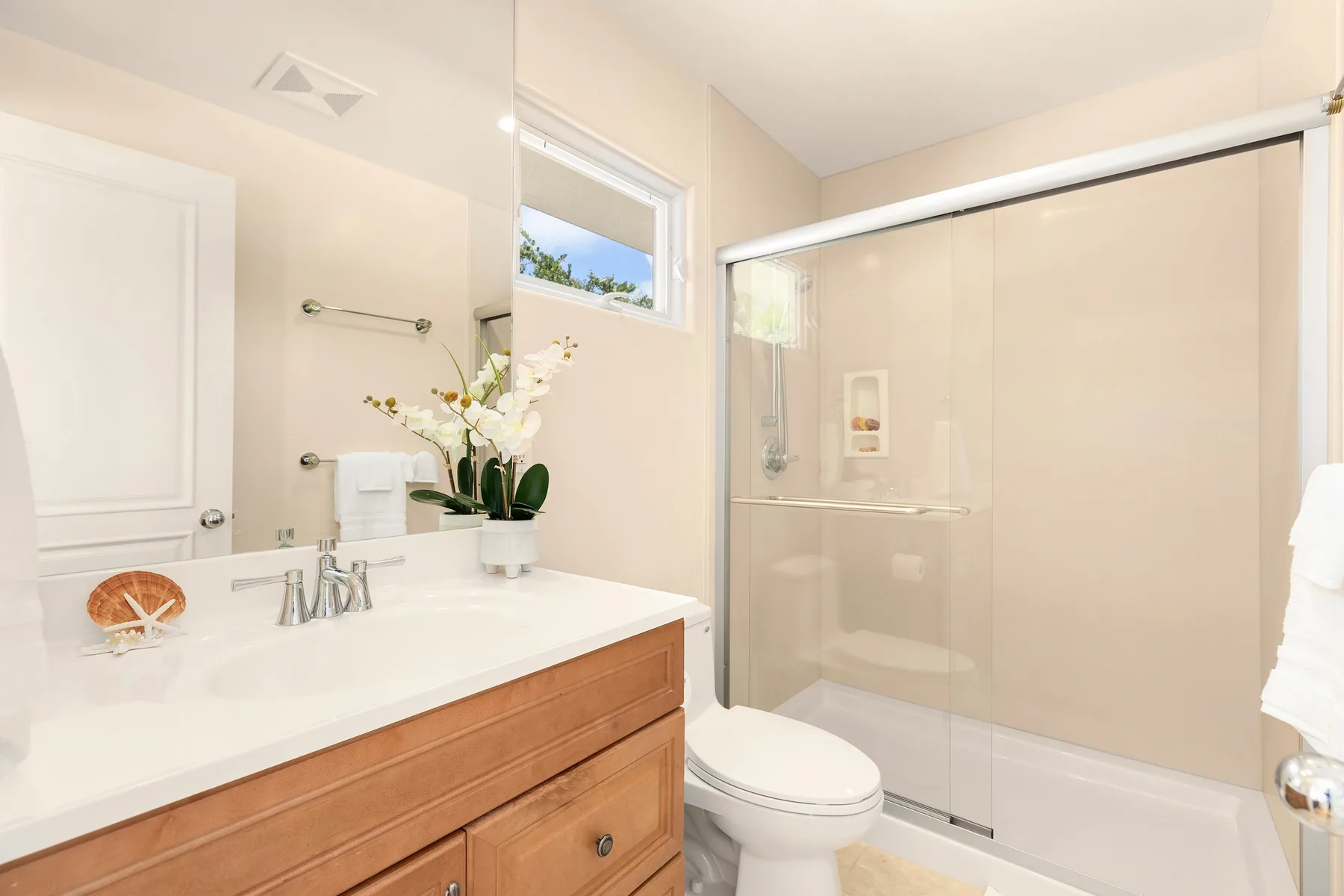 Un baño luminoso con tocador, lavabo y ducha de vidrio.