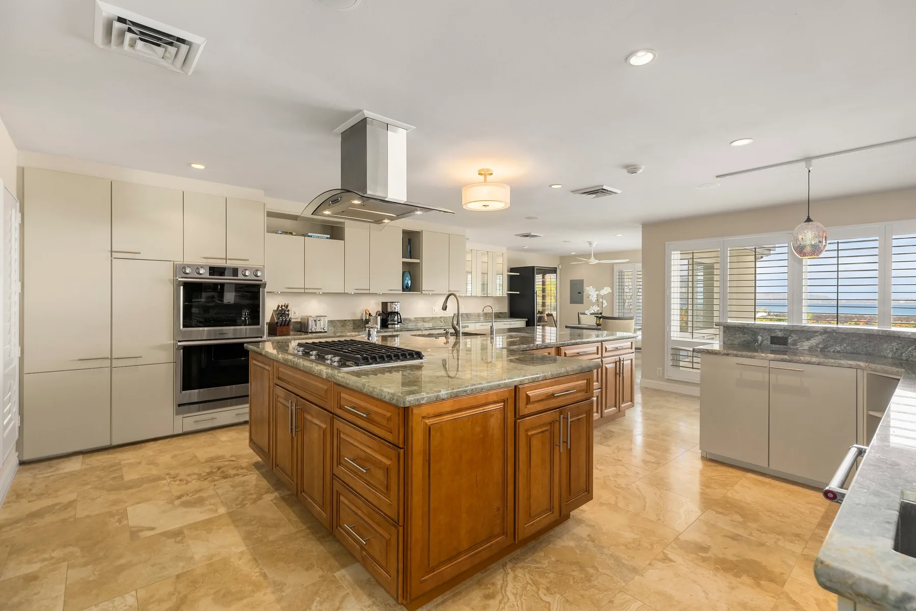 Una cocina amplia con una isla central de madera y grandes ventanas.