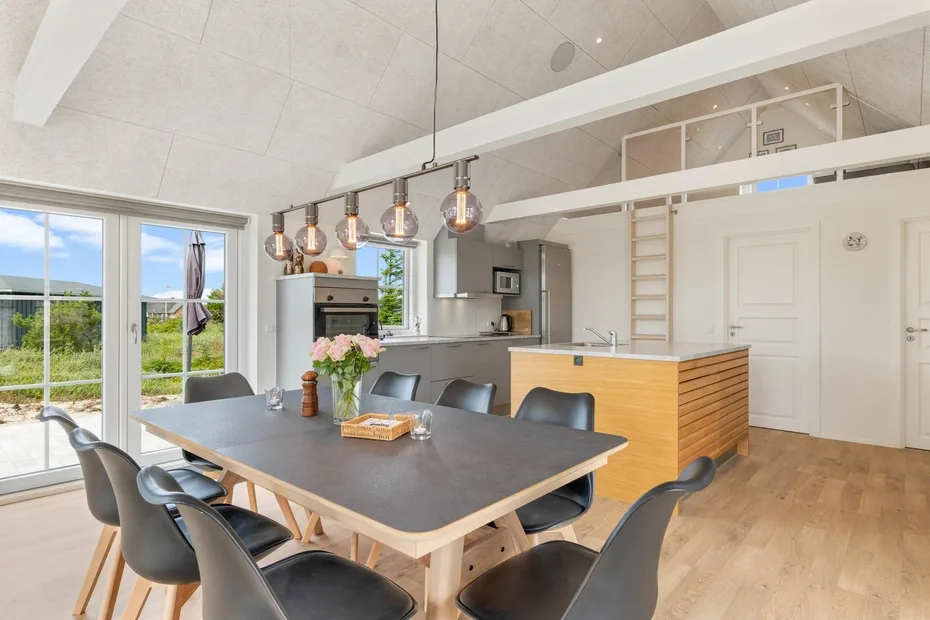 Una luminosa cocina-comedor de espacio abierto con una mesa larga e isla.
