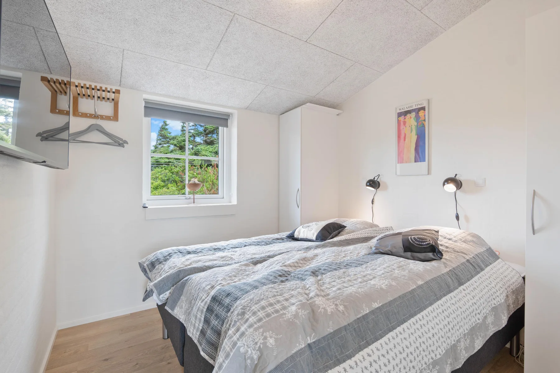 Dormitorio con dos camas cubiertas con ropa de cama gris estampada y una ventana.