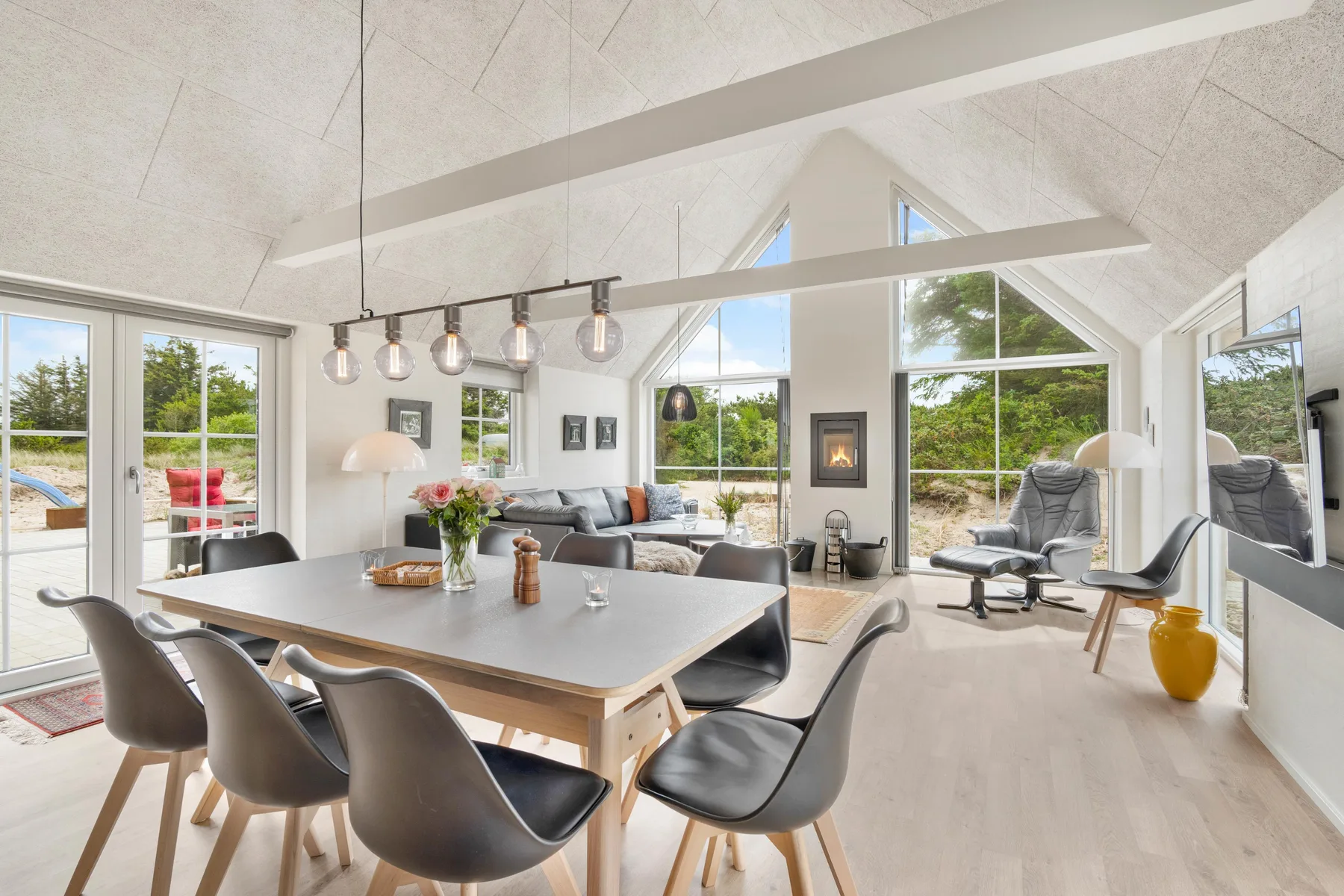Una luminosa sala-comedor de planta abierta con grandes ventanas y una mesa de comedor alargada.