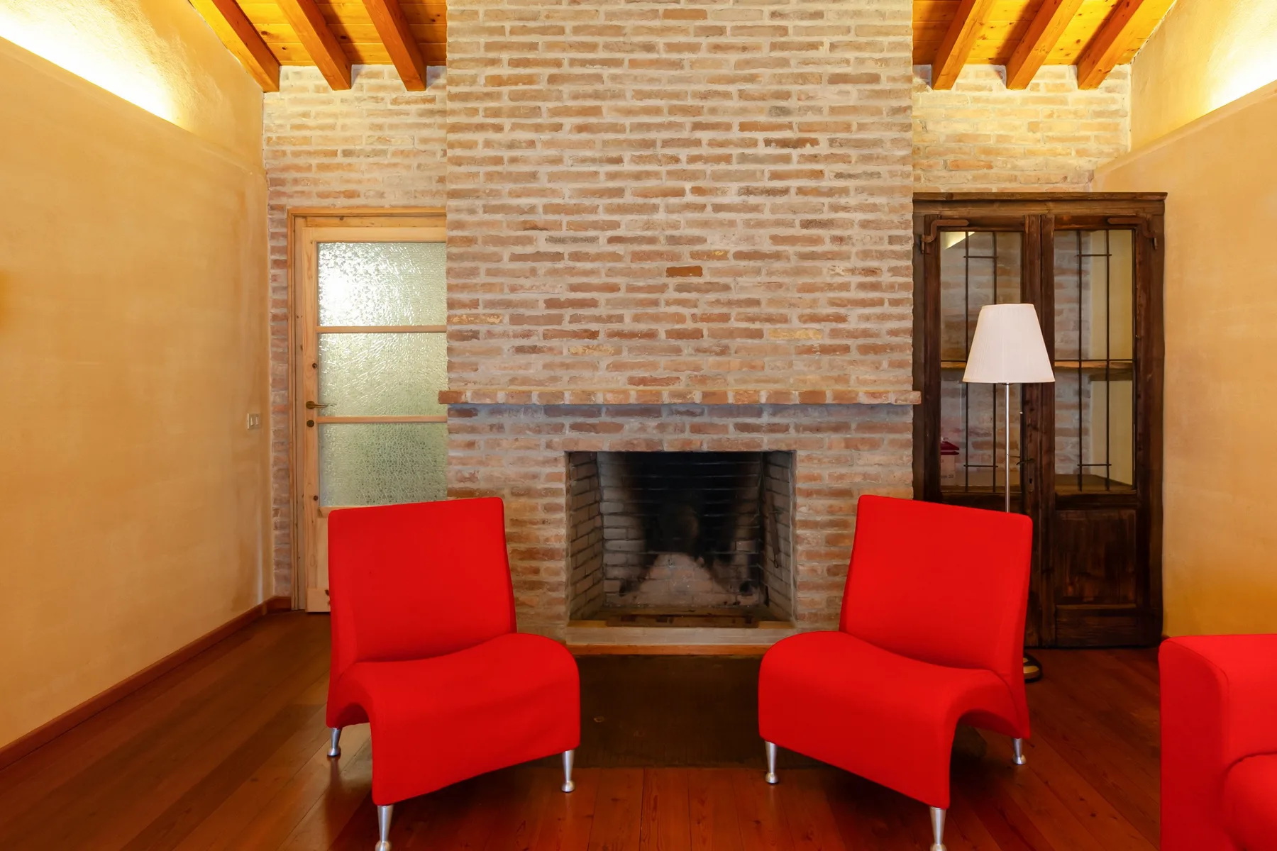 A brick fireplace stands between red seating in a warm-toned living room.