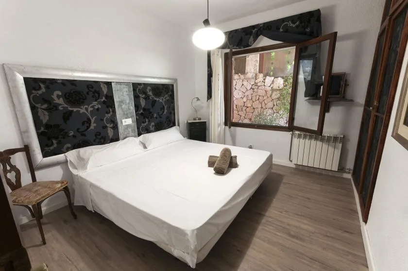 A bedroom with a large bed, patterned headboard, and open window.