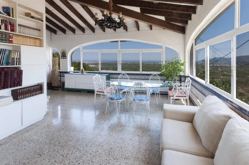 A bright living and dining area with large windows overlooking the countryside.