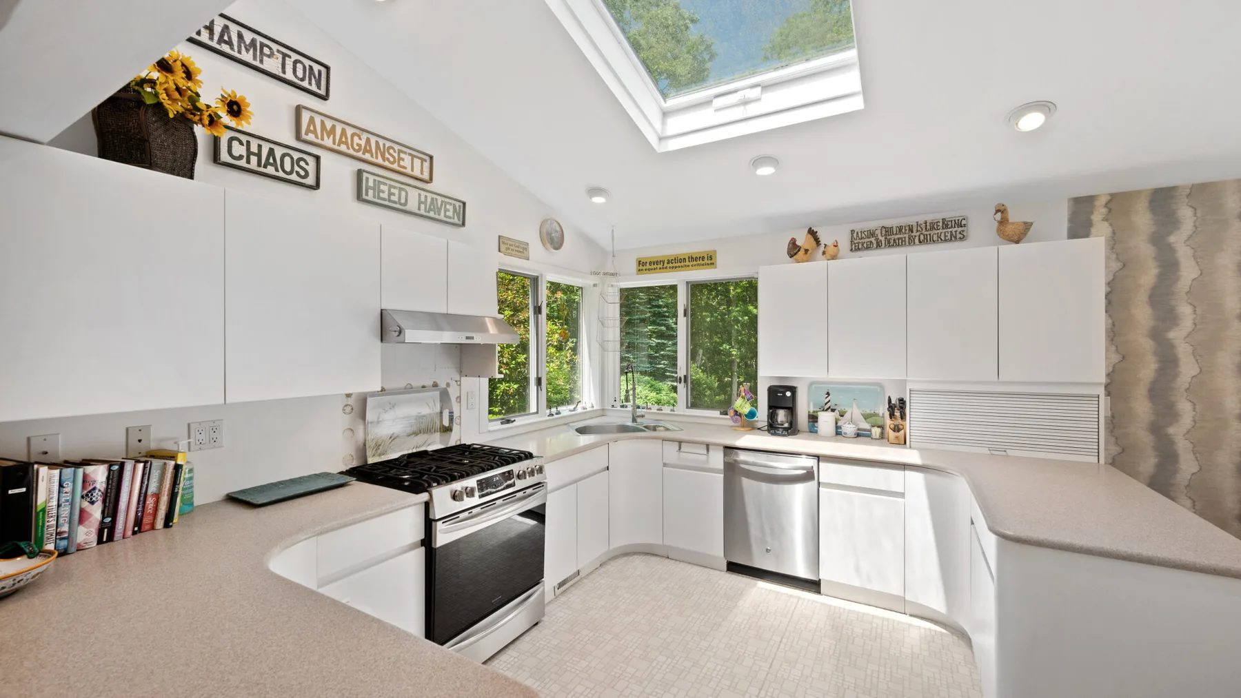 Bright white kitchen with wraparound counters, a stove, and a skylight.