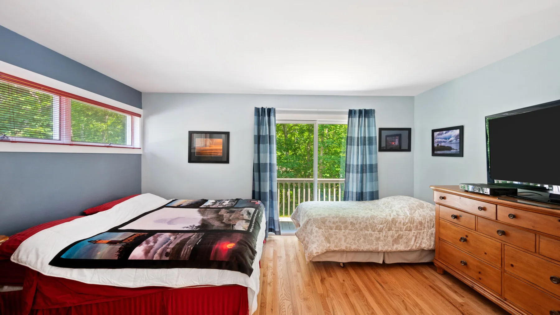 A bedroom with two beds, curtained windows, and a wooden dresser.