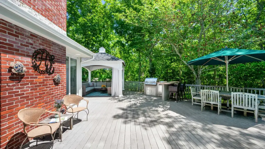 An outdoor deck with seating, a covered patio area, and a large green umbrella.