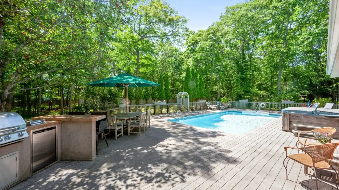 A backyard pool area with a dining table and outdoor seating.