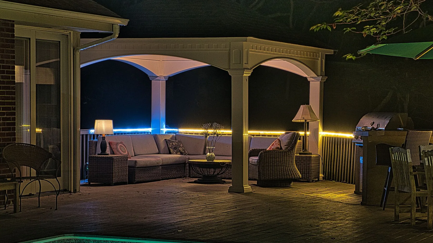 A covered outdoor patio has seating beneath an arched pergola.