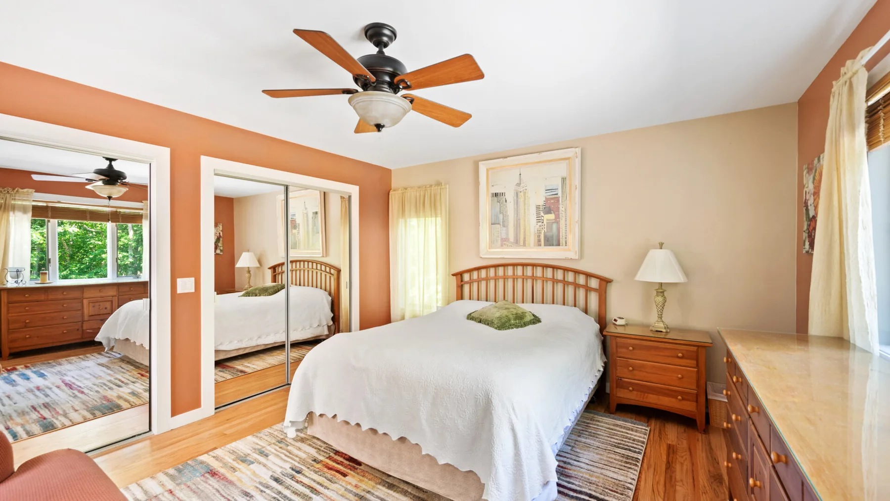 A bedroom with a bed, wooden dressers, and a ceiling fan.