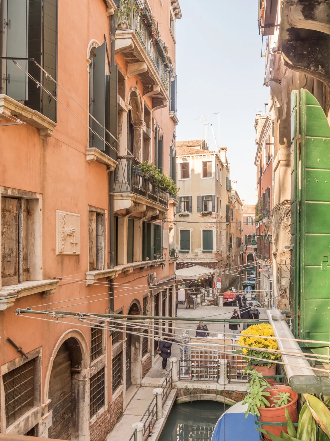 A narrow canal runs between closely spaced buildings, with a small pedestrian bridge.