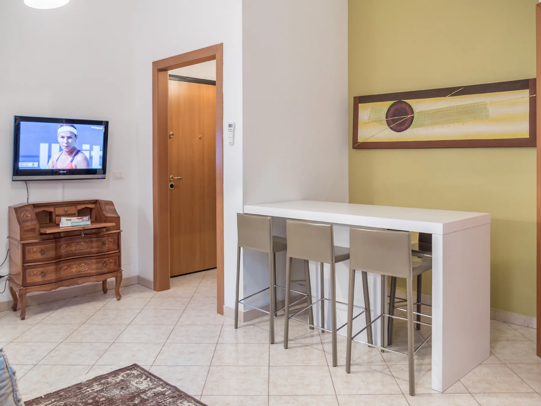A dining area with a white counter and seating beside a wooden door.