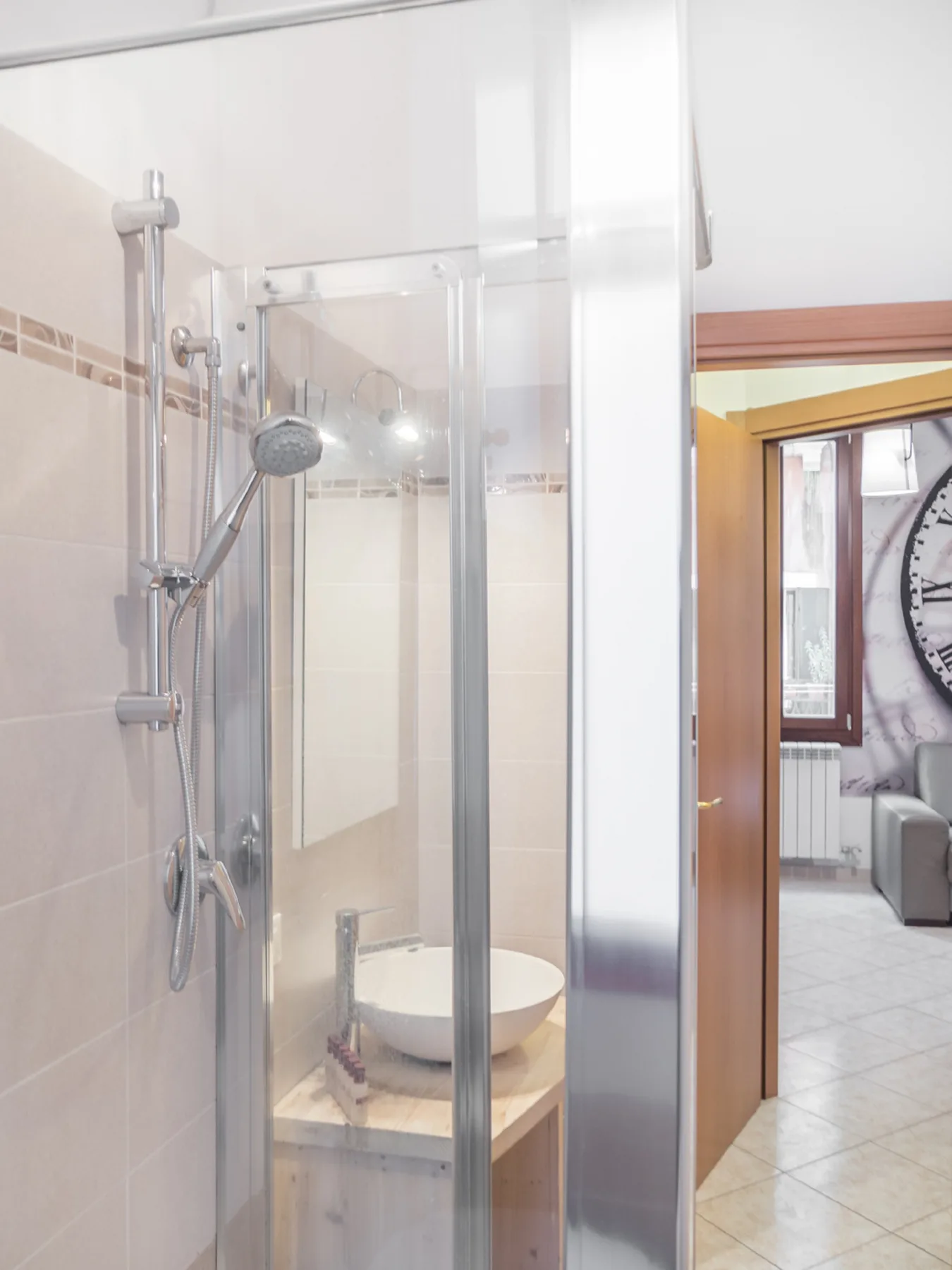 A tiled bathroom with a glass shower and a sink.