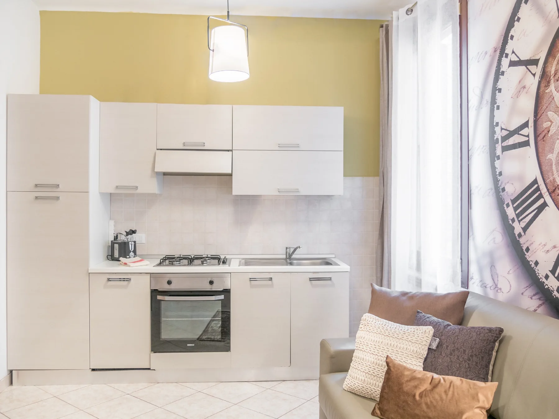 A compact kitchen with white cabinets and a seating area beside the window.