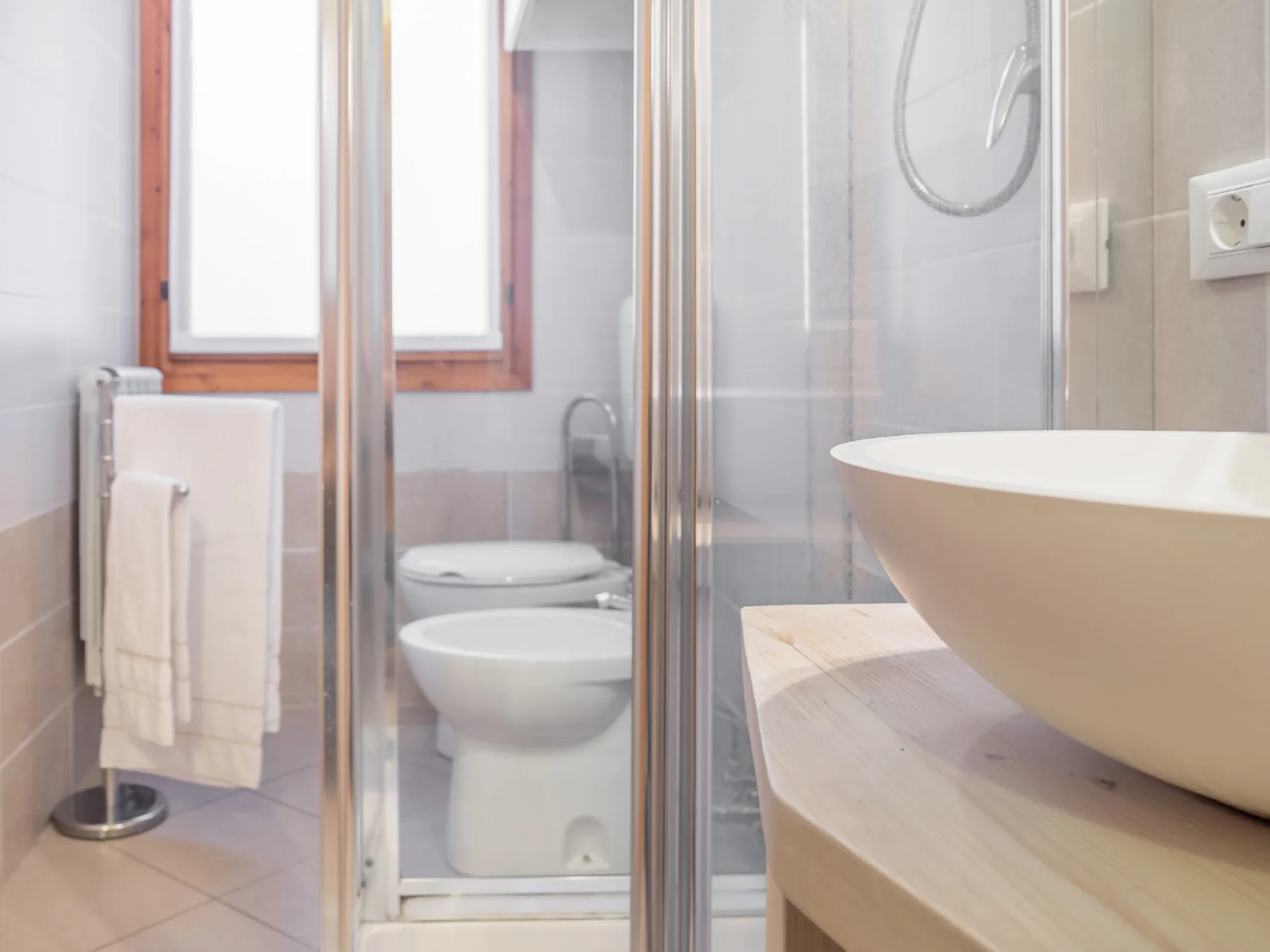 A bathroom with a glass shower and a vessel sink on a counter.