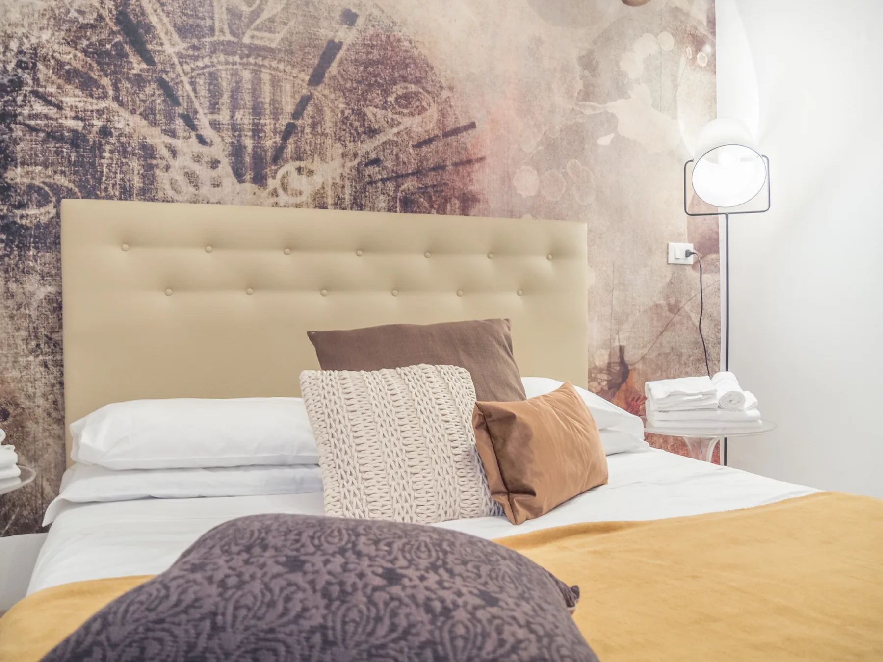 A bedroom with a bed dressed in white linens and decorative pillows.