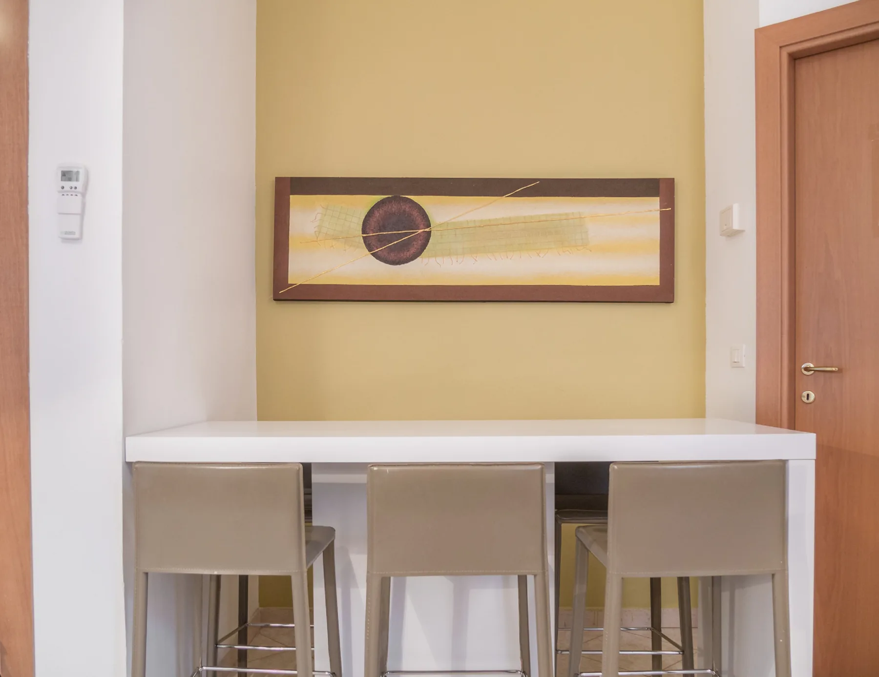 A dining area with a white counter and seating beneath framed artwork.