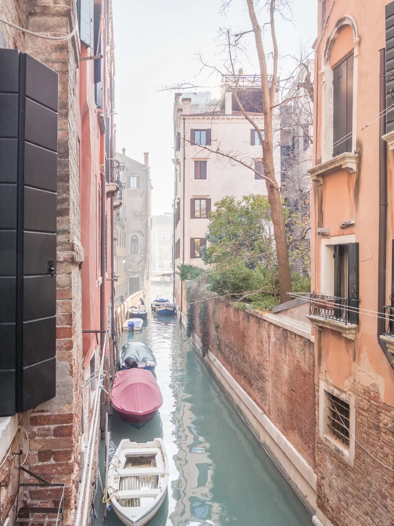 A narrow canal runs between buildings, with small boats moored along the water.