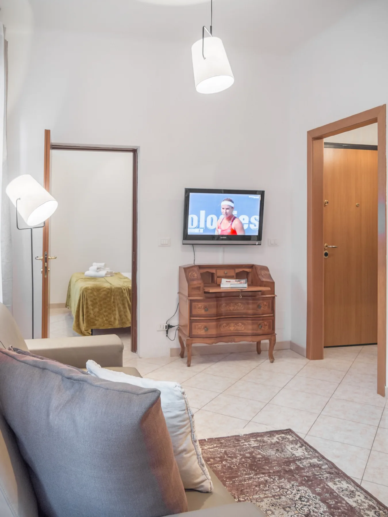 A bright living room with a wooden chest beneath a wall-mounted television.