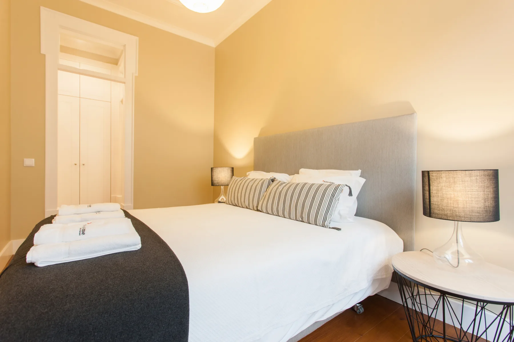 Un dormitorio con una cama bien arreglada y lámparas de mesilla.