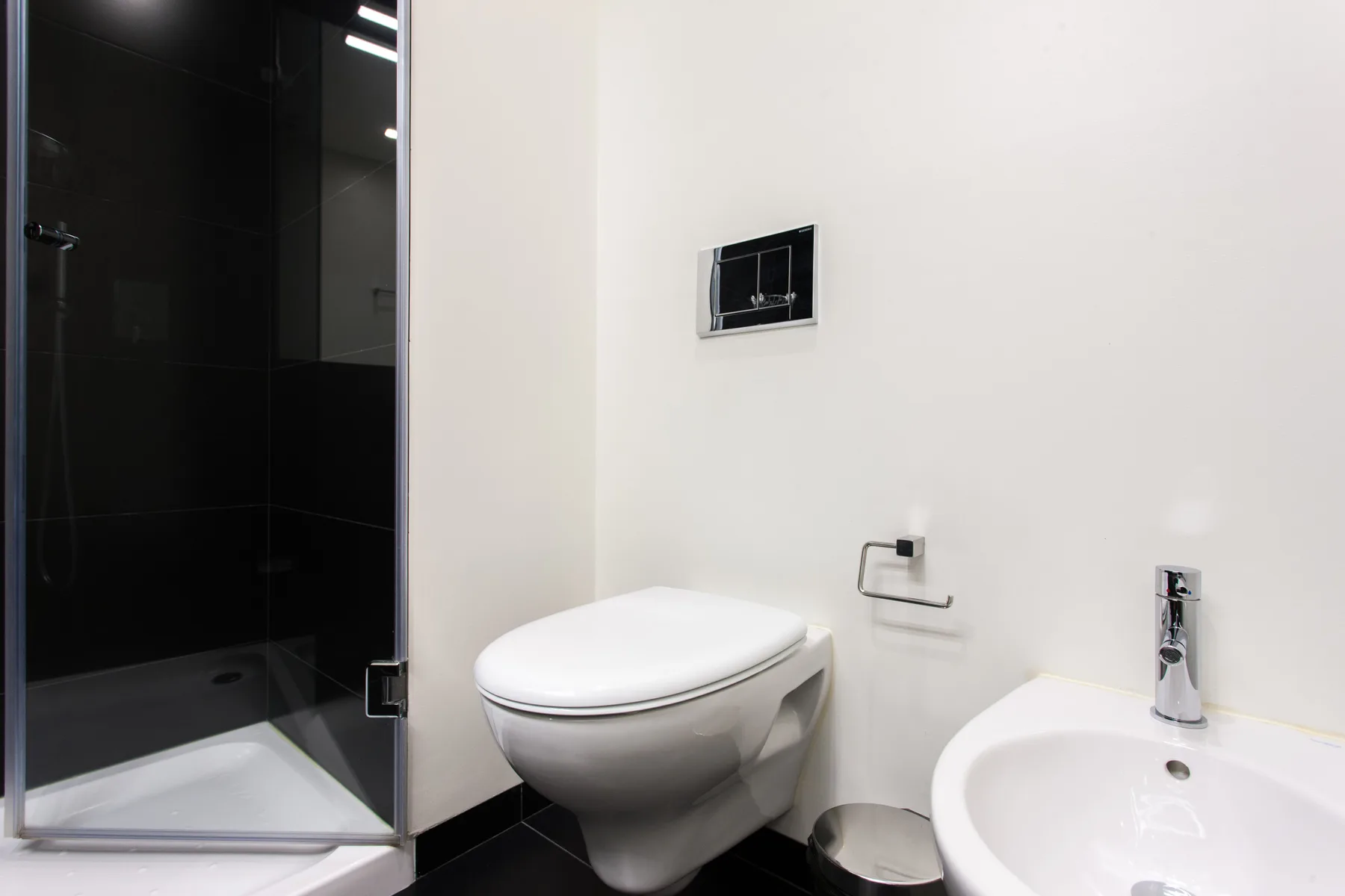 Un baño con inodoro, lavabo y ducha de cristal.