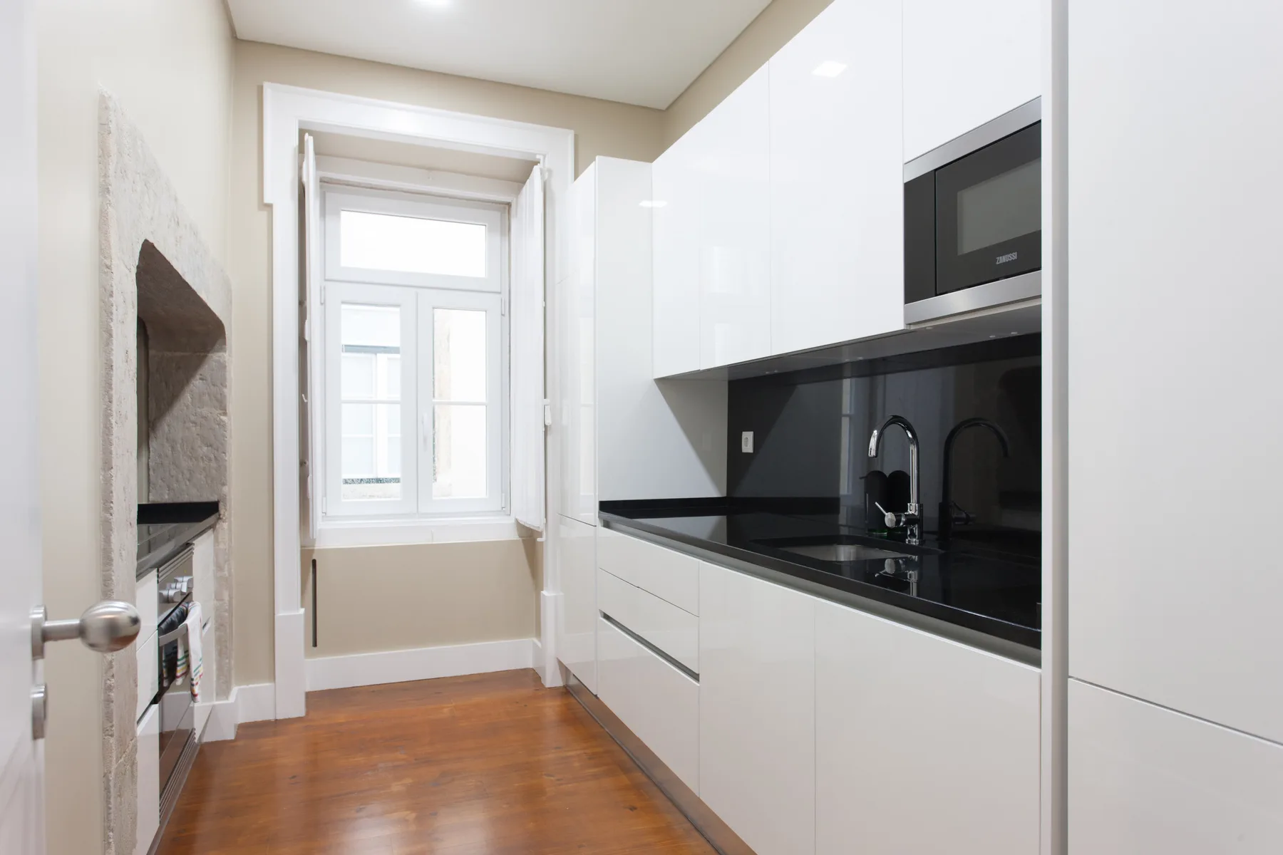 Una cocina luminosa con armarios blancos, encimeras oscuras y una ventana.