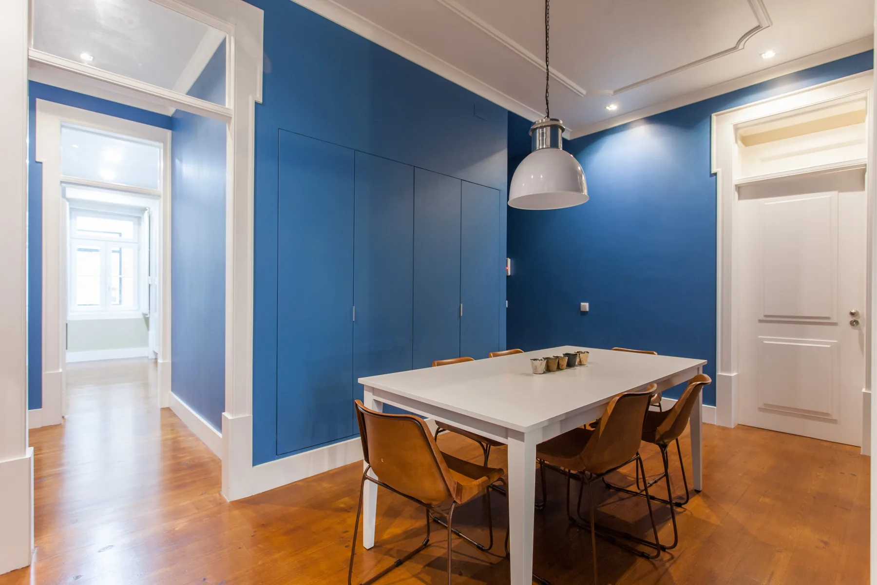 Un comedor con una mesa blanca y sillas junto a paredes azules.