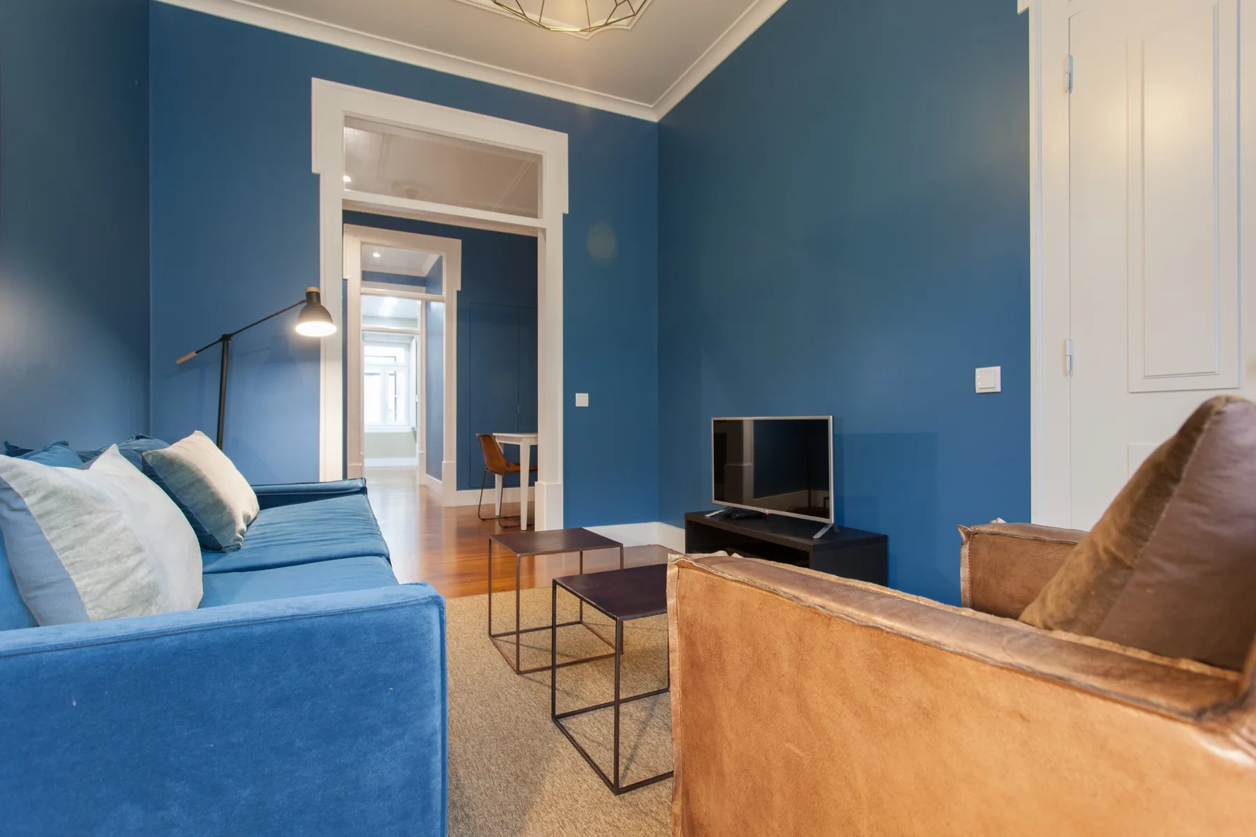 Sala de estar con paredes azules, asientos, un televisor y una mesa de centro.