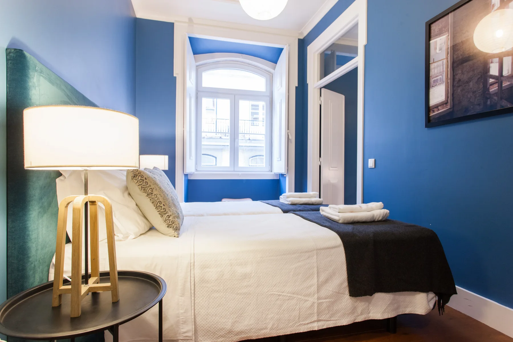 Dormitorio con una cama, paredes azules y una ventana.